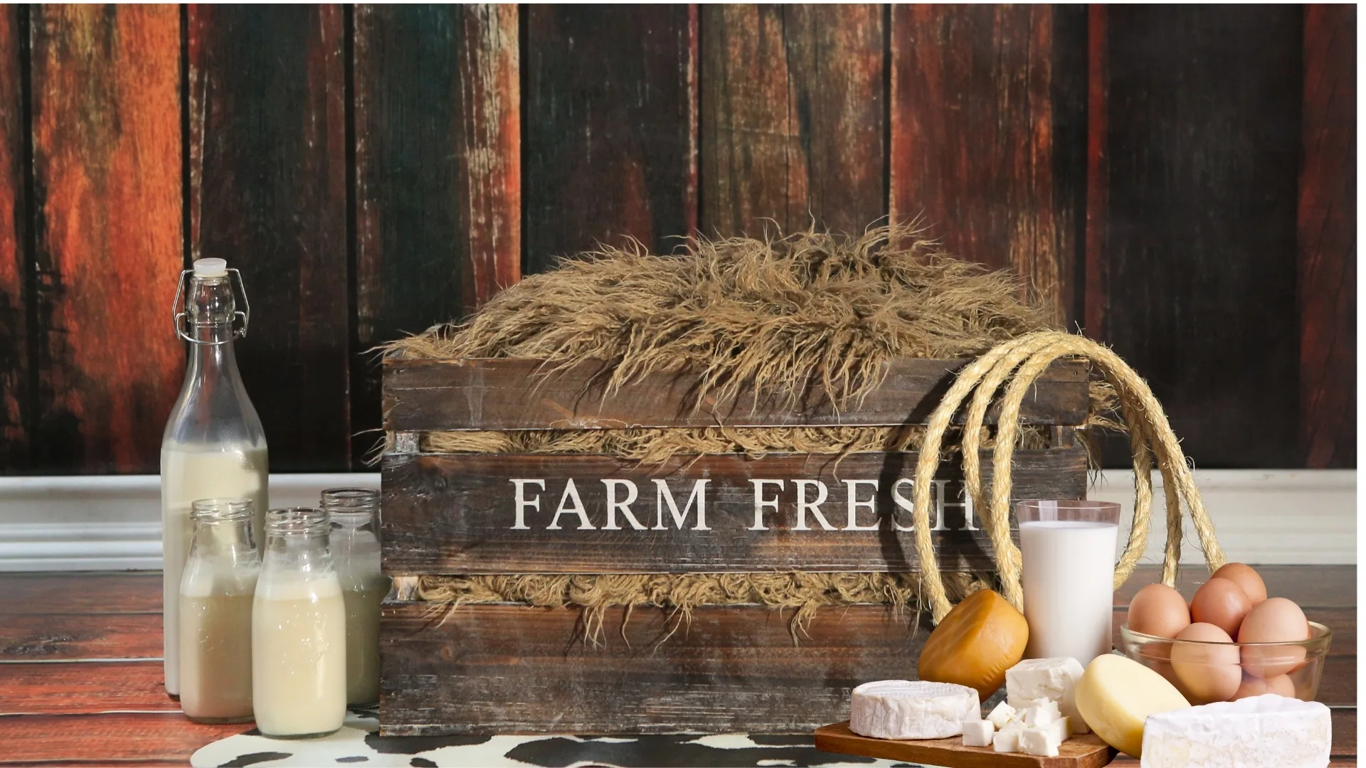 Productos de granja sobre una mesa de madera, con leche, quesos, mantequilla, huevos y una caja rústica, que simbolizan las pequeñas elecciones concretas que apoyan a los campesinos y refuerzan una alimentación más soberana.